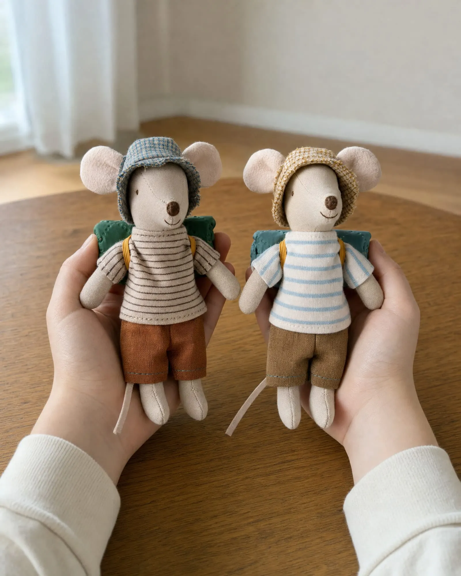 Two Maileg hiker mice held in a child's hands.