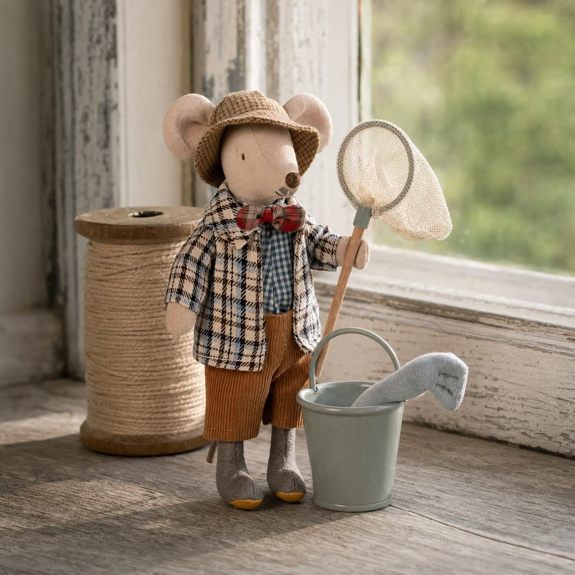 Maileg granddad mouse on a windowsill with the mouse fishing set net, bucket and knitted fish beside twine