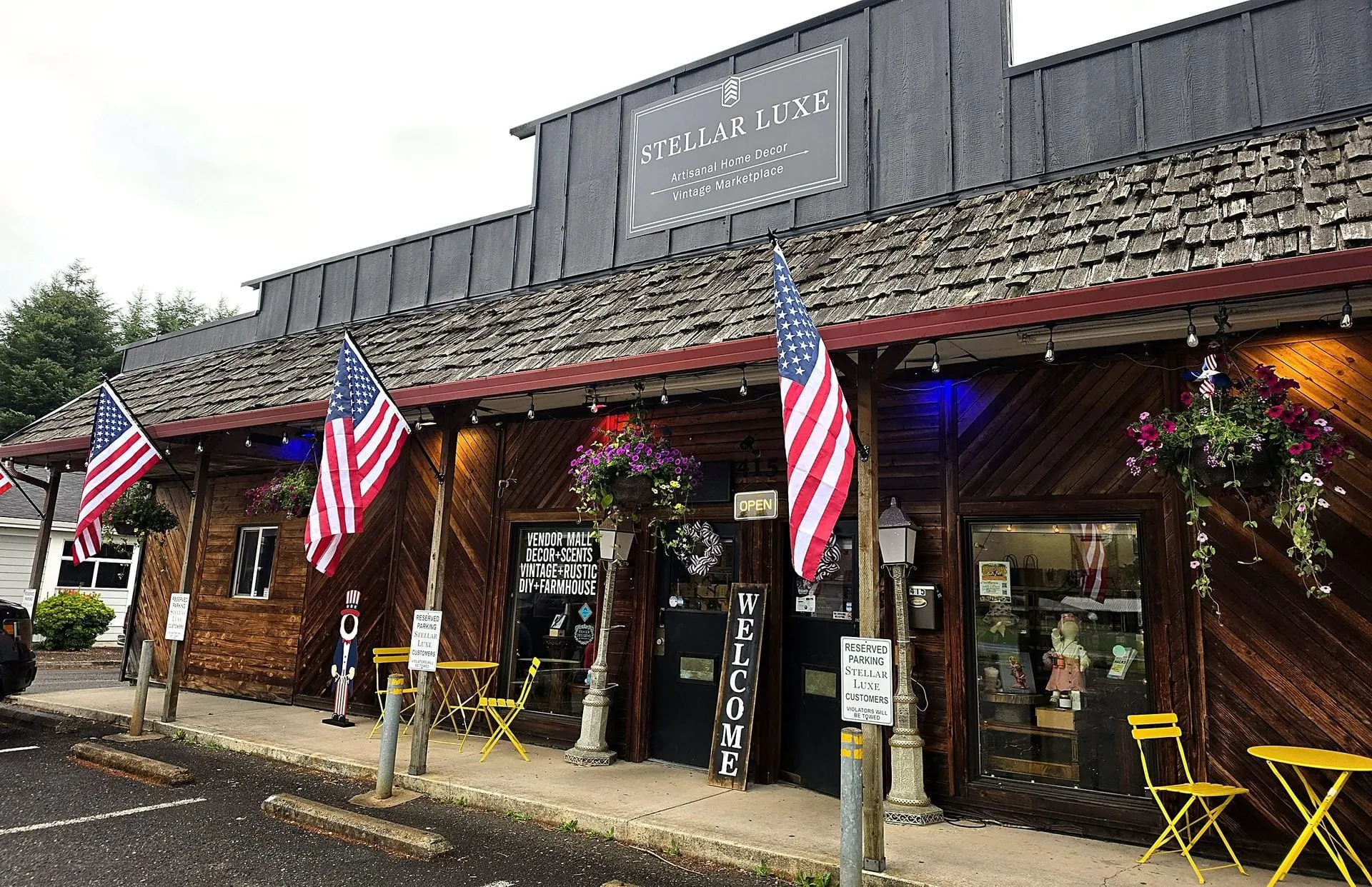 The Stellar Luxe storefront on Amboy Avenue in Yacolt, Washington — flags flying and yellow bistro chairs out front